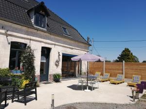 a patio with an umbrella and chairs and a table at La maison de mon enfance in Delettes