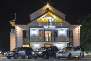 Tre camion parcheggiati di fronte a una casa di notte di Hotel Patriot a Mestia