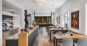ein Restaurant mit Tischen und einer Frauenstatue in der Unterkunft Alpen Hotel München in München