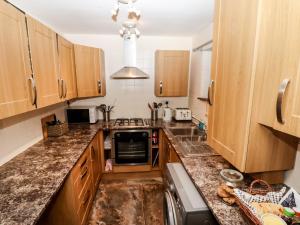 a kitchen with wooden cabinets and a sink at Bendigedig in Blackburn