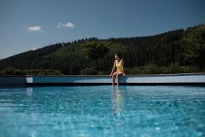 a woman is standing on a boat in the water at Hotel Traube Tonbach in Baiersbronn