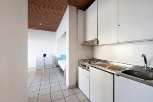 a kitchen with white cabinets and a sink at Residence La Cava Trilocale 1d in Pognana Lario