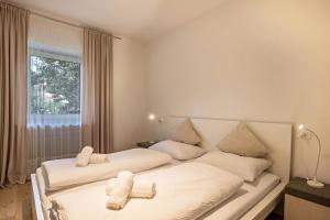 1 dormitorio con 2 camas con sábanas blancas y ventana en Apt Hofer Sandra, en Villabassa