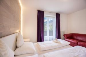 a hotel room with a bed and a red couch at Apt Hofer Elisabeth in Villabassa