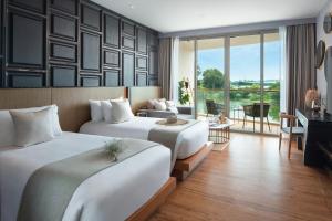 a hotel room with two beds and a living room at Wyndham Grand Nai Harn Beach Phuket in Nai Harn Beach