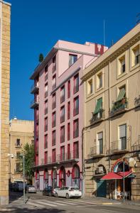 un edificio rosa con coches estacionados frente a él en Tgna Reial 1 en Tarragona