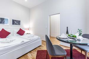 a hotel room with a bed, table, chairs and a television at The Levante Rathaus Apartments in Vienna