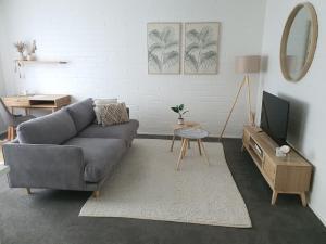 sala de estar con sofá gris y TV en Royal Park Retreat, en Melbourne