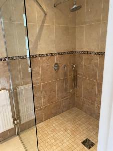 a shower with a glass door and a tile floor at The little house in West Hanningfield