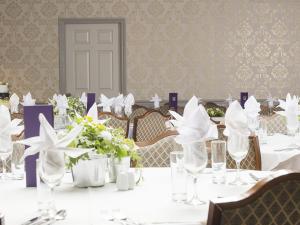 a dining room with white tables and chairs with flowers at The Birdham At Bembridge in Bembridge