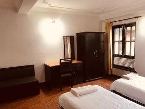 Habitación con 2 camas, escritorio y silla. en Hotel Little Buddha Inn, en Katmandú