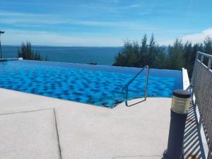 a large swimming pool with a view of the ocean at Grandbeach 1 condo A202 in Rayong