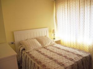 een slaapkamer met een bed en een raam met een sprei bij Saromar I Apartament amb gran terrassa, per 6 persones a 5 minuts de la Platja Gran in Platja  d'Aro