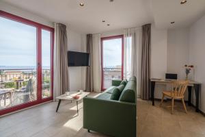 a living room with a green couch and large windows at Tgna Reial 1 in Tarragona