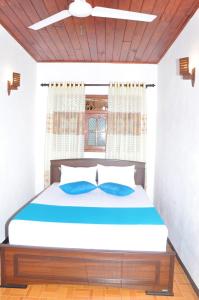 a bedroom with a large bed with blue pillows at Sidangana House Ahangama in Ahangama
