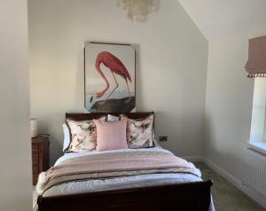 a bedroom with a bed with a picture of a flamingo at Church View Cottage, Drift House Holiday Cottages in Congleton