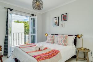 a white bedroom with a bed with a towel on it at 211 De Waterkant Piazza in Cape Town