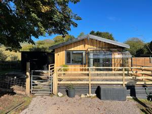 a small wooden building with a window and a fence at Spacious lodge with king sized bed in Inveraray