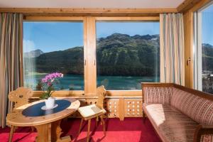 um quarto com uma mesa, um sofá e uma janela grande em Chesa Languard em St. Moritz