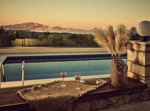 a table with two glasses of wine next to a pool at Lithakia Balcony Villa in Lithakia