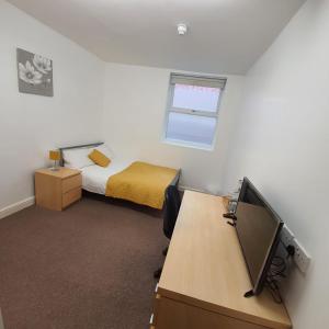 a bedroom with a bed and a desk with a computer at D19 SANGHA HALL in Leicester