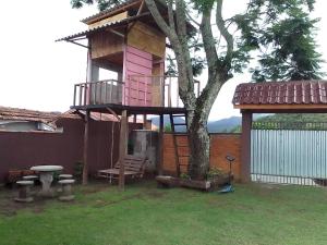 una casa en el árbol con un banco y una mesa en Casa de Tijolinho Penedo-RJ, en Penedo