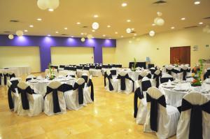un salón de banquetes con mesas y sillas blancas en Hotel Bello Veracruz en Veracruz