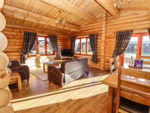 Cabaña de madera con sala de estar con sofá y TV. en Holly Lodge en Oakham