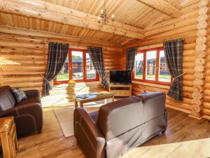 a living room with a couch and a tv in a log cabin at Holly Lodge in Oakham