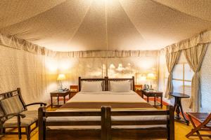 a bedroom with a large bed and two chairs at Jungle Cave Resort in Sawāi Mādhopur