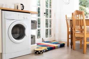 a white washing machine in a kitchen with a chair at Beersbridge Cottage near Titanic Centre & Airport in Belfast