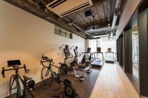 un gimnasio con bicicletas y equipos de ejercicio en una habitación en obi Hostel, en Tokio