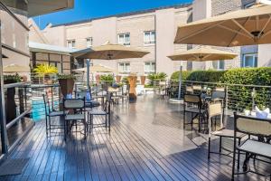 un patio al aire libre con mesas, sillas y sombrillas en City Lodge Hotel Johannesburg Airport, Barbara Road, en Kempton Park