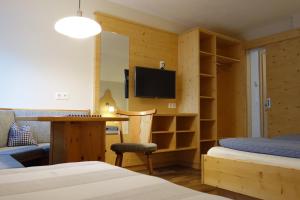 a room with two beds and a desk with a television at Zum Fuhrmann in Neustift im Stubaital