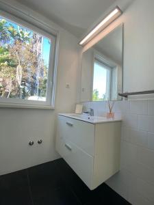 ein weißes Bad mit einem Waschbecken und einem Fenster in der Unterkunft Belém Fantastic Triplex House in Lissabon