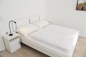 ein weißes Bett mit weißer Bettwäsche und einer Lampe auf einem Nachttisch in der Unterkunft Vienna4you App 33 you are welcome in Wien