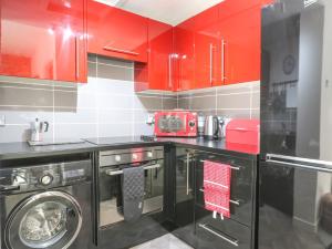 a kitchen with red cabinets and a washing machine at The Coorie Cove in Helensburgh