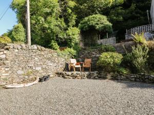 a stone wall with a chair next to a table at The Coorie Cove in Helensburgh