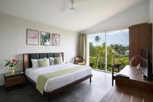 a bedroom with a bed and a desk and a window at Sibaya Beach Resort, Morjim in Morjim