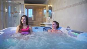 Duas mulheres estão sentadas numa banheira de hidromassagem. em Dwór Maria Antonina em Strzyżów