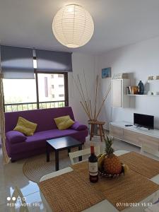 salon z fioletową kanapą i stołem w obiekcie Apartamentos El Carmen w mieście Morro del Jable +33 zdjęcia