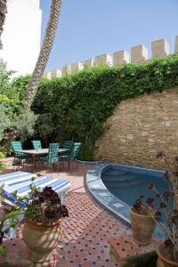 a patio with a pool and chairs and a table at Aghata Palms Riad in Essaouira