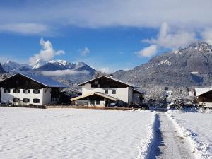 una casa en la nieve con montañas en el fondo en Landhaus Hochgern, en Unterwossen