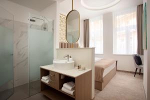 uma casa de banho com um lavatório, uma cama e um espelho. em Mera Hotel em Budapeste