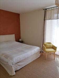 a bedroom with a bed and a chair and a window at Auberge Buissonniere in Gresse-en-Vercors