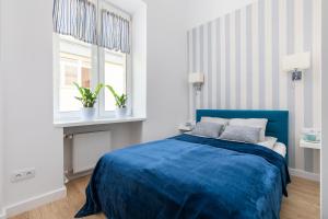 a bedroom with a blue bed and a window at Apartament Królewska by Your Freedom in Warsaw