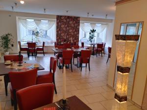 a dining room with tables and chairs and windows at Hotel Evabrunnen in Bischofswerda