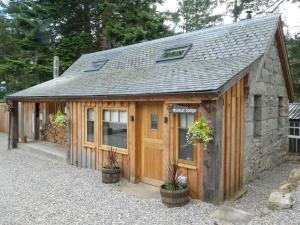 a small wooden building with plants in front of it at Wildcat Lodge in Boat of Garten