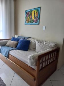 a couch with blue pillows and a painting on the wall at Apartamento na Prainha in Arraial do Cabo