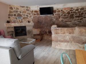 a living room with a stone fireplace and a couch at La Lagareta de Olivia in Trevejo